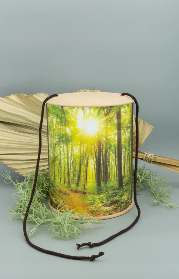 Eine rundum bedruckte Fotourne mit Wald und Sonnenstrahlen inklusive der Ablasskordel und dekorativem Hintergrund